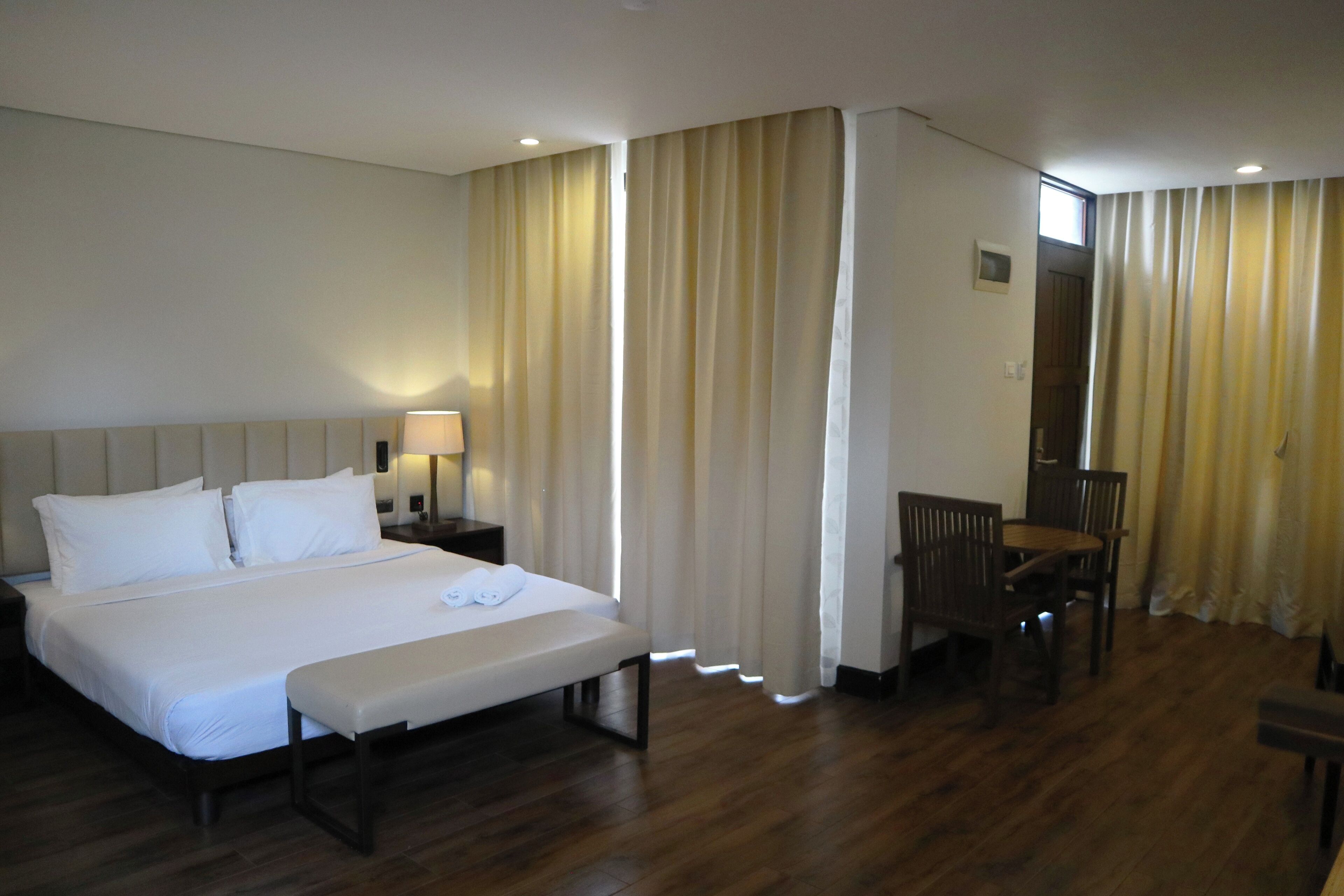 A hotel room with a large bed, bedside tables, a desk, and a chair.