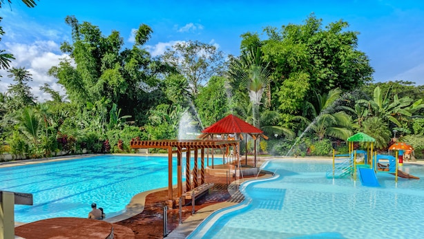 Una piscina con muelle de madera, un tobogán y un pabellón.
