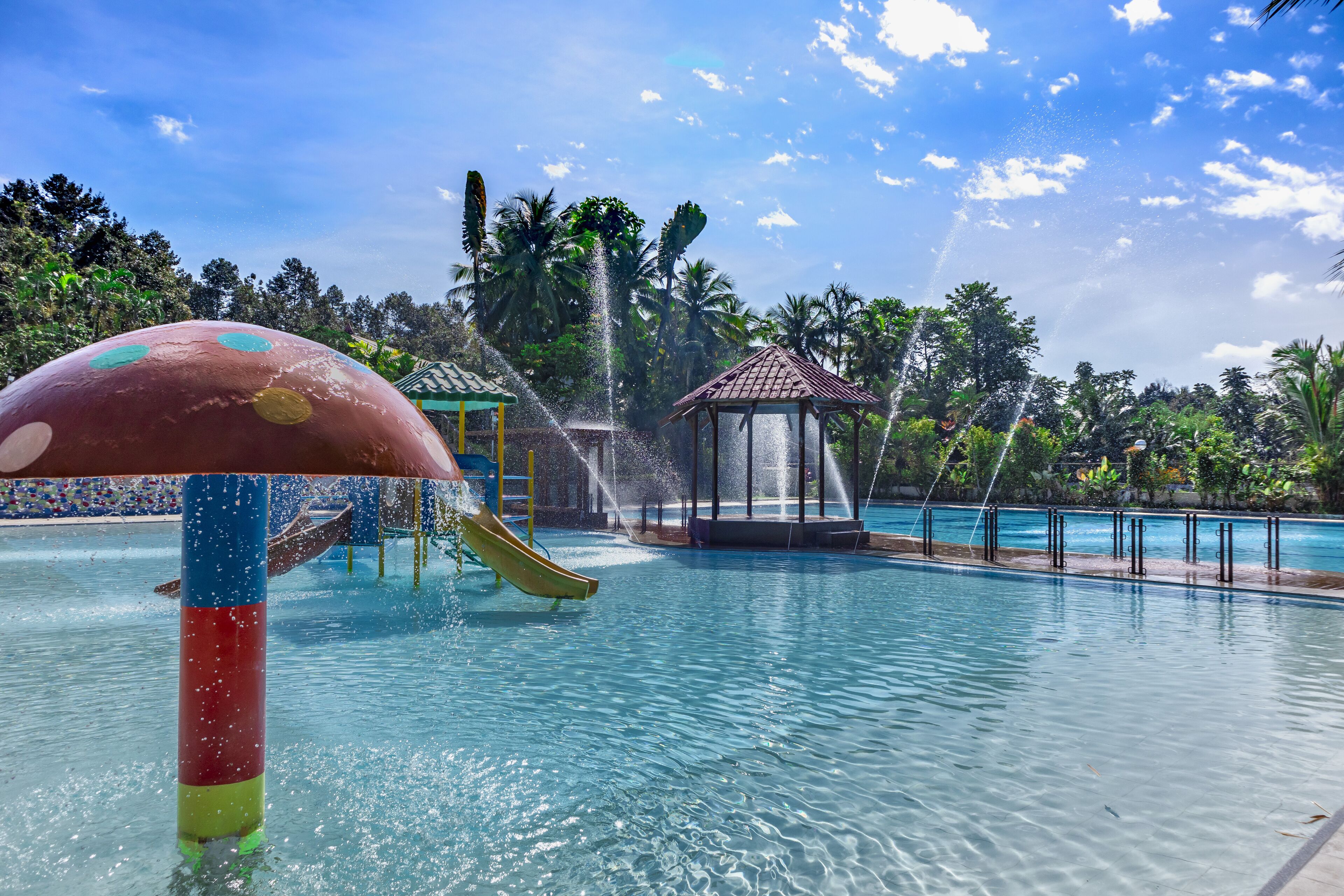 A water park with a slide, a water fountain, and a gazebo.