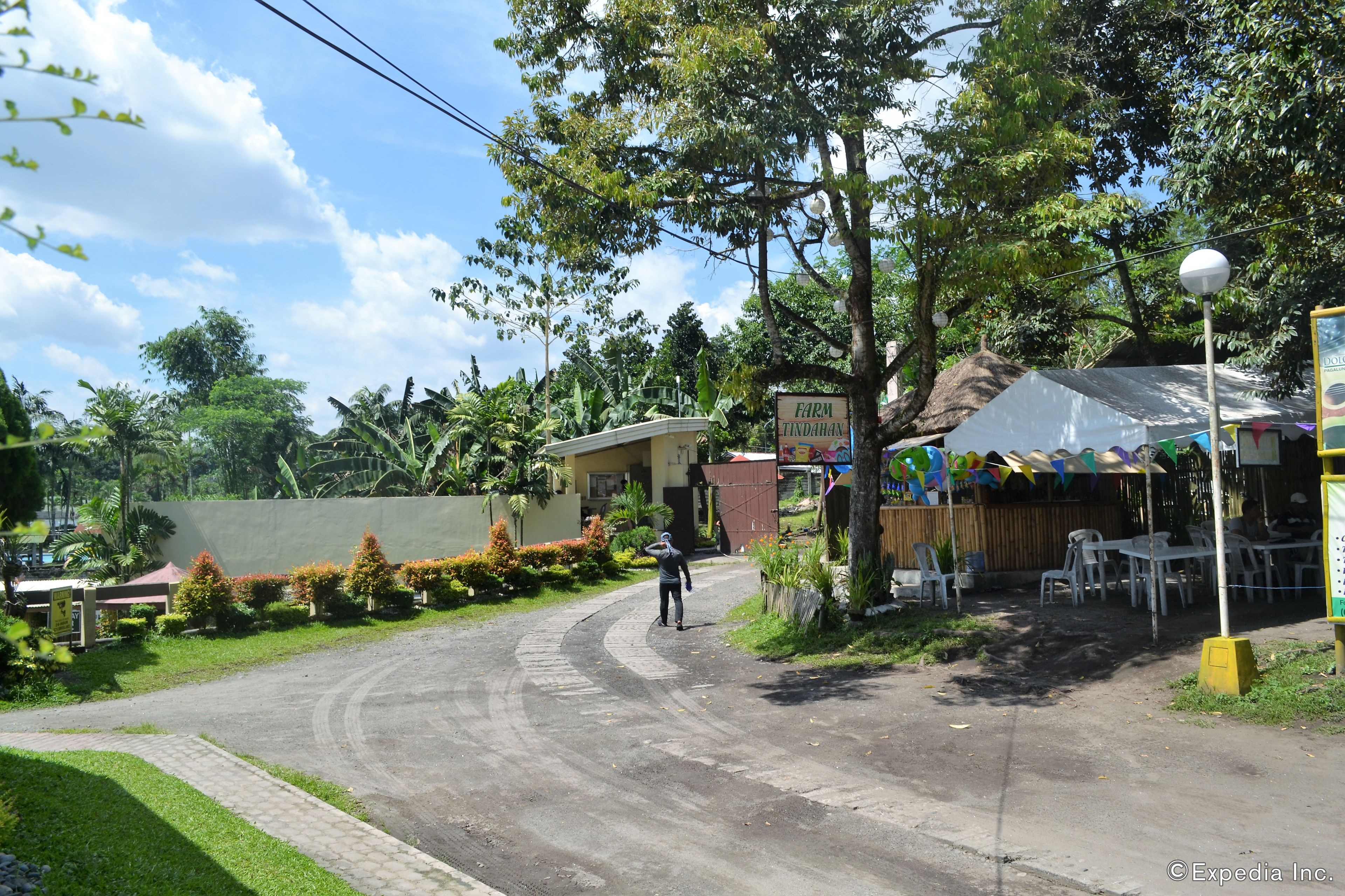 A paved road curving to the right with a sign for 'Farm Findahaan' and a covered area with tables and chairs.