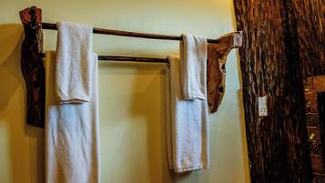 A wooden towel rack with three white towels hanging.