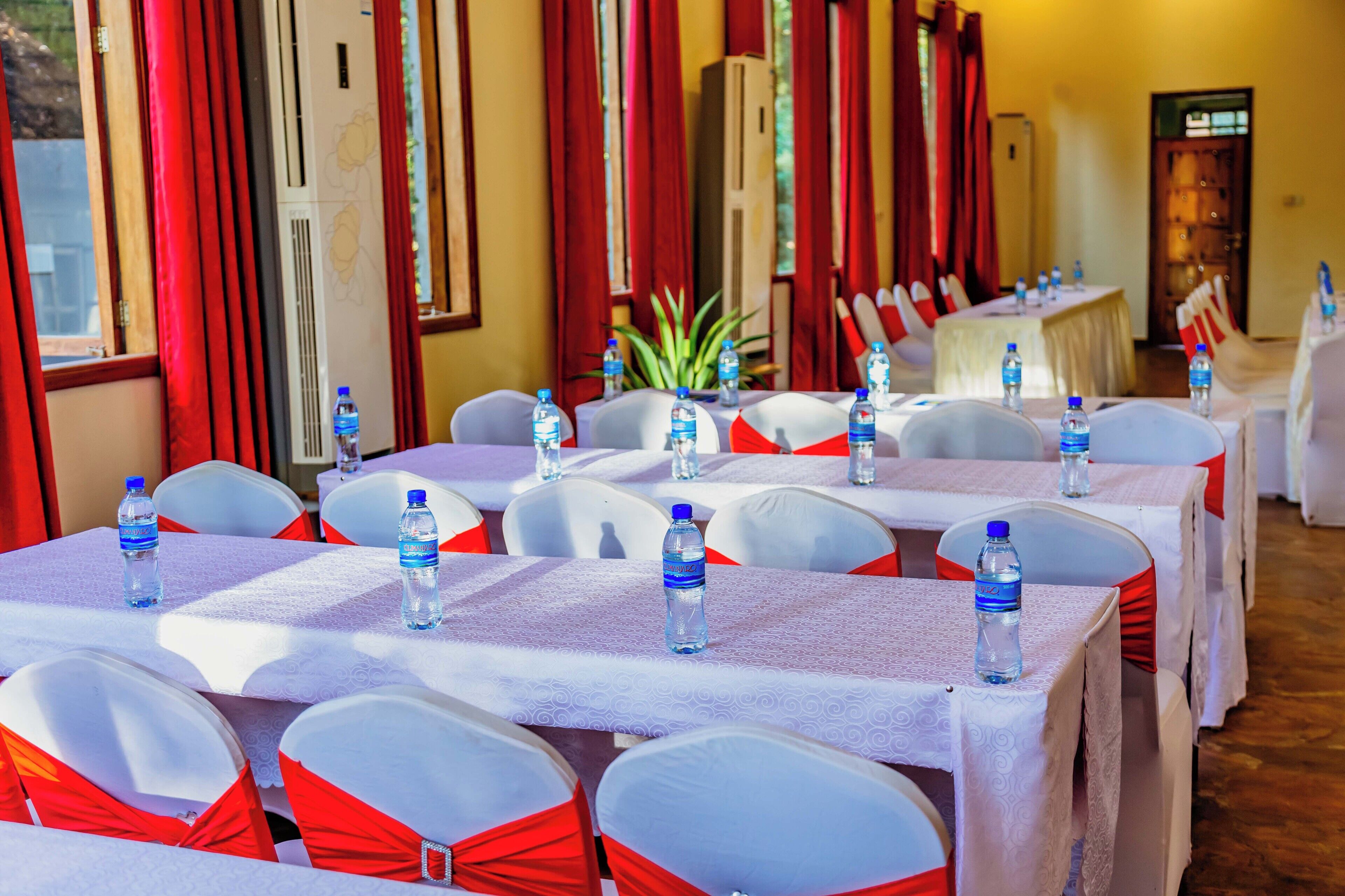 A conference room with tables set for a meeting, each with a water bottle and white tablecloths.