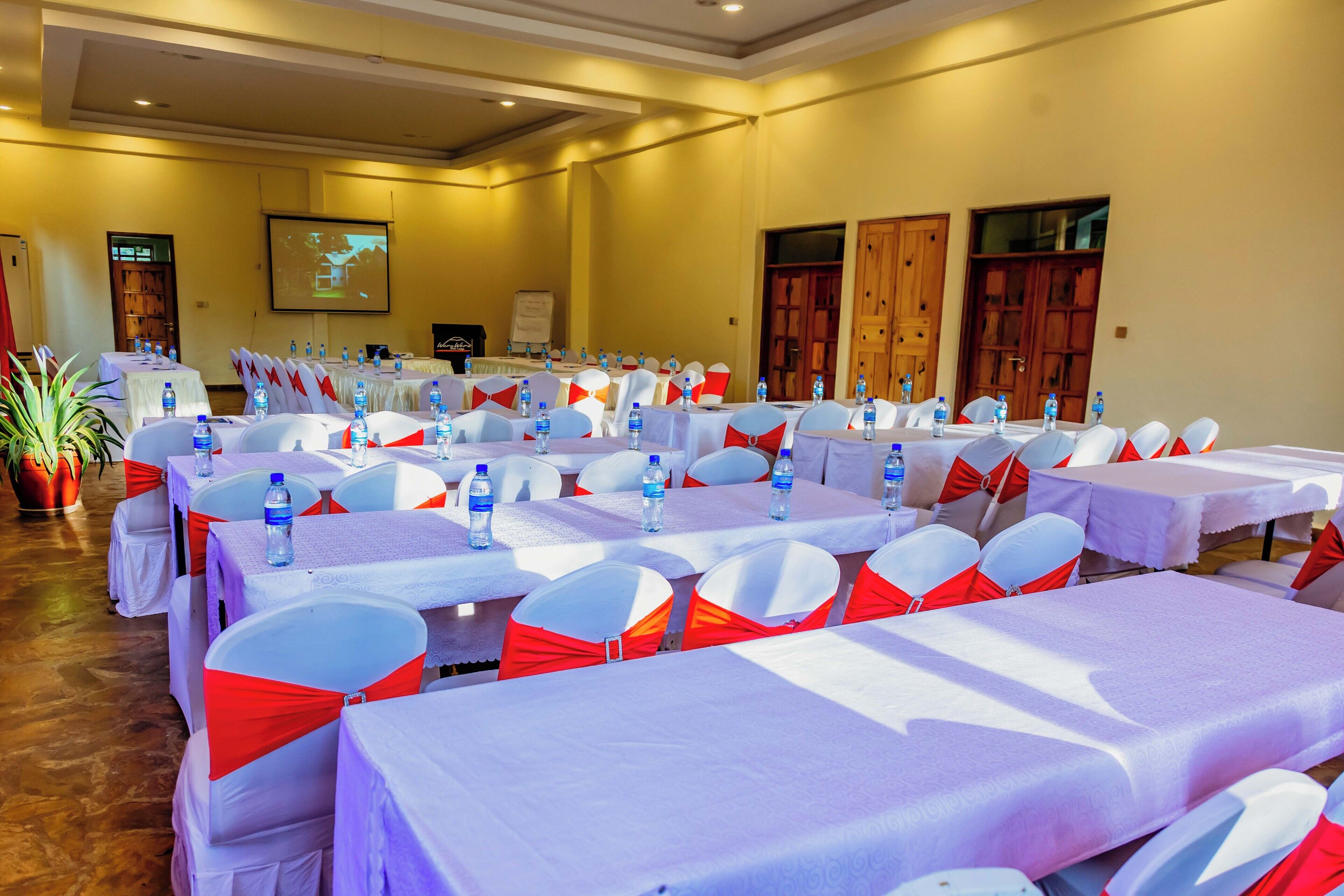 A conference room with multiple tables, each with water bottles and red sashes.