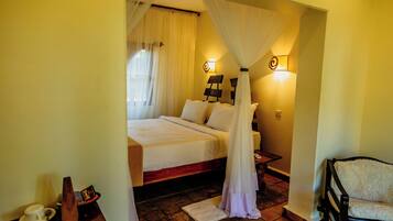 A bedroom with a bed, bedside table, chair, and a nightstand with a lamp.
