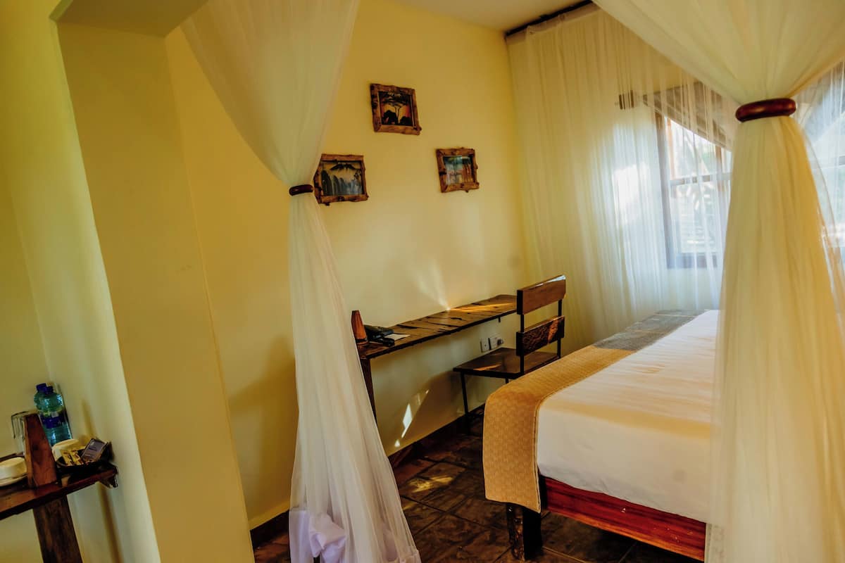 A room with a bed, a desk, and a chair. There are three framed pictures on the wall.