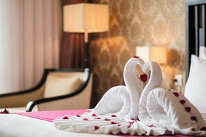 Habitación de hotel con una cama, una silla, una lámpara y un diseño decorativo en la pared.