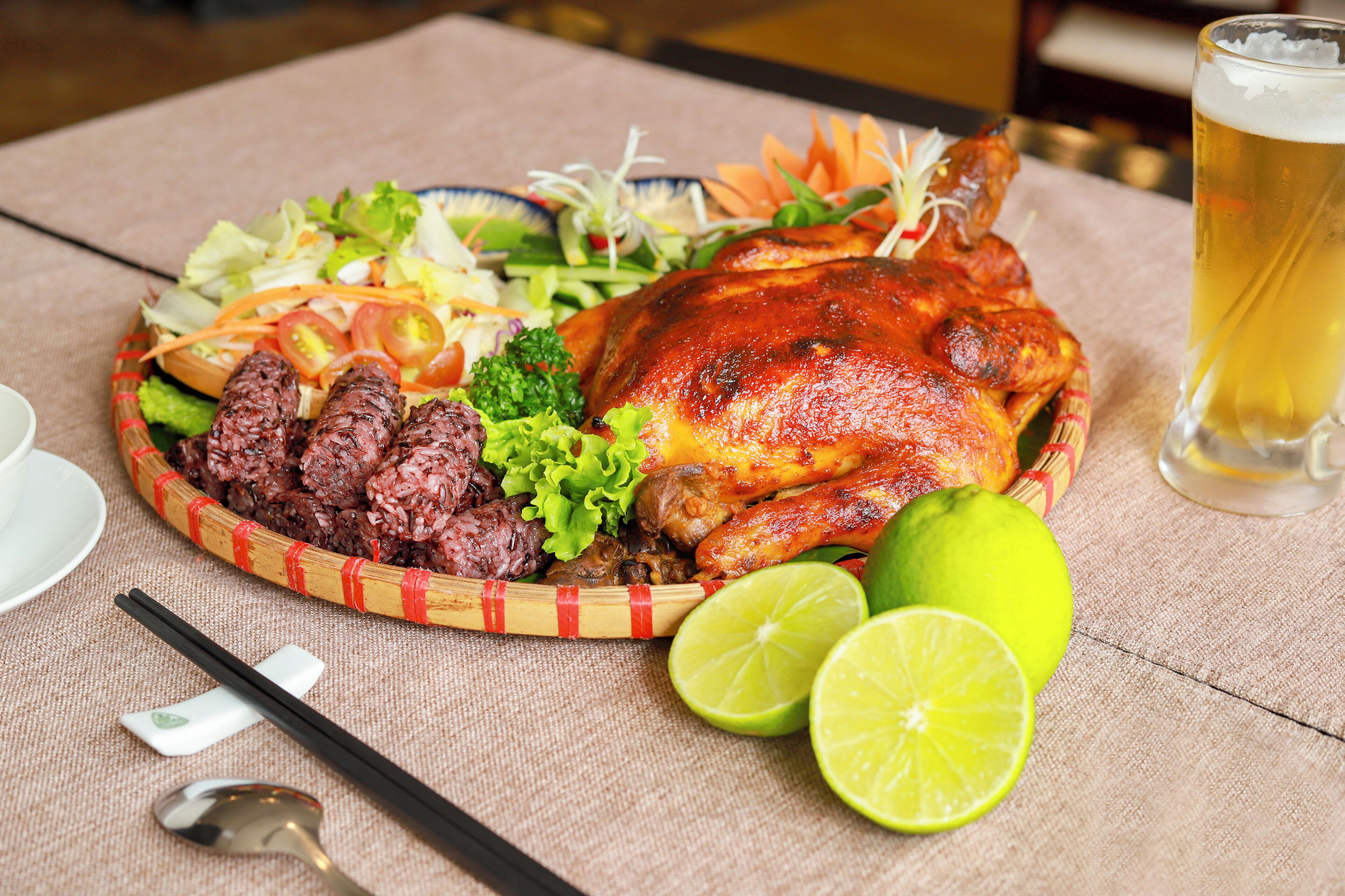 Un repas composé d’un poulet rôti, de riz, de légumes et d’un verre de bière, le tout servi sur une table.