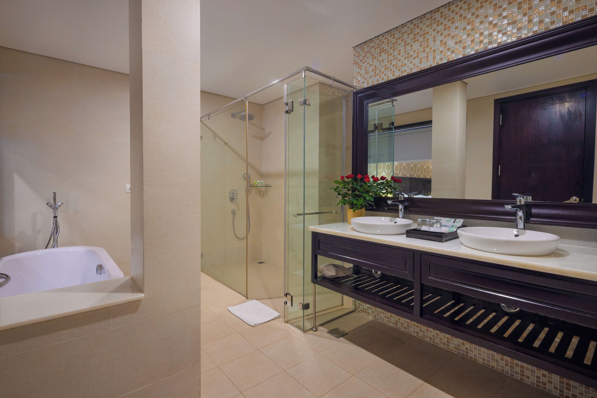 A modern bathroom with a glass-enclosed shower, two sinks, a large mirror, and a dark wood vanity.