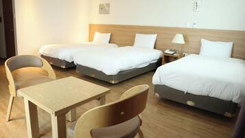 Una habitación de hotel con dos camas, una mesa de madera y dos sillas.