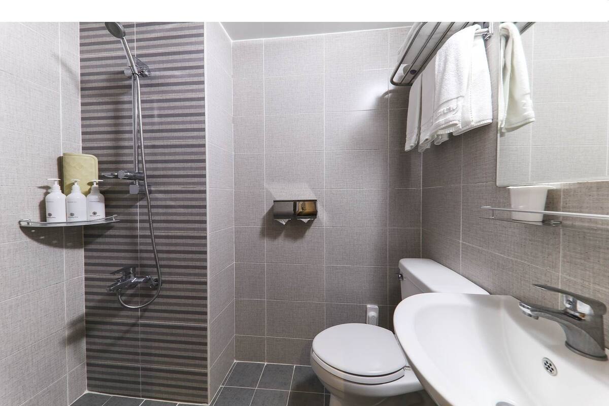 A modern bathroom with a shower, toilet, and sink.