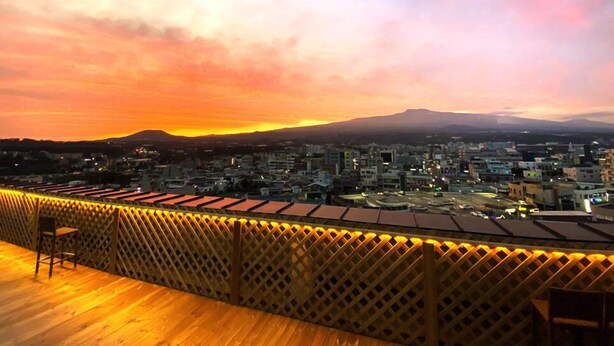 Una terrazza sul tetto con vista sulla città e su una montagna al tramonto.