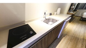 Una cucina moderna con piano cottura a induzione integrato, lavello in acciaio inossidabile e una lavastoviglie compatta.