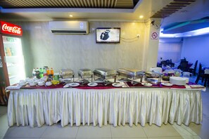 A buffet setup with multiple serving stations, a Coca-Cola refrigerator, and a television mounted on the wall. - Hotel Lake Breeze (Dhaka)