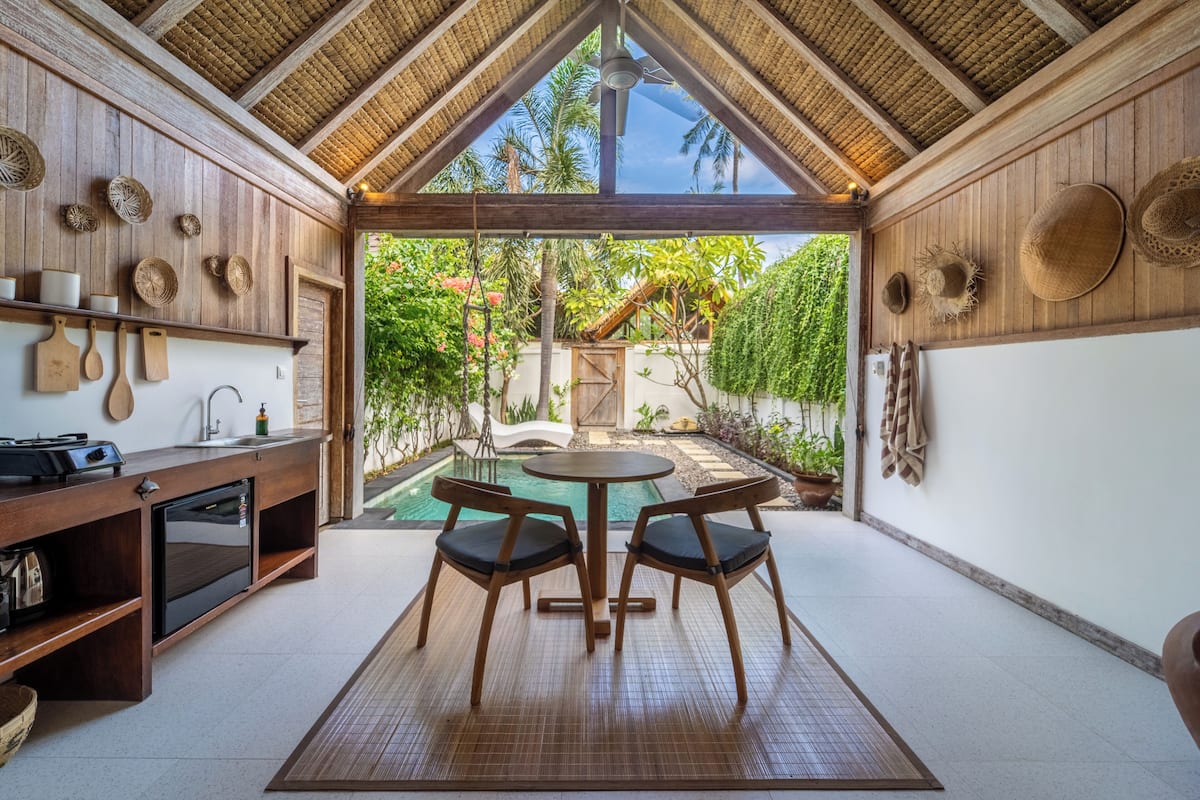 A kitchen with wooden cabinets, a built-in oven, and a dining area with a table and chairs.