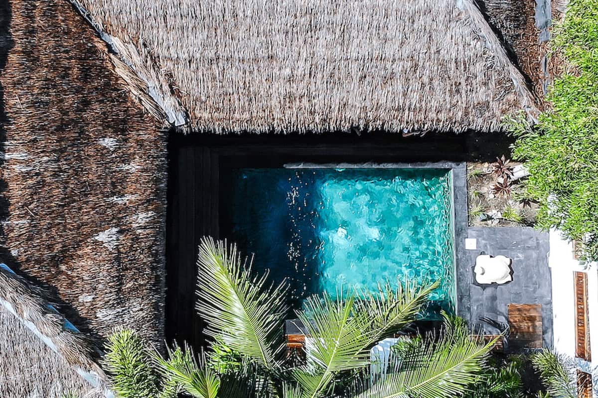 A thatched-roof structure with a clear blue pool.