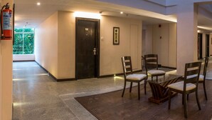 A hotel lobby with a reception desk, chairs, a fire extinguisher, and framed artwork on the walls. - Mango Hotels Prangan, Bhubaneshwar (Bhubaneshwar)