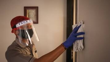 Una persona con visor facial y guantes limpiando una pared.
