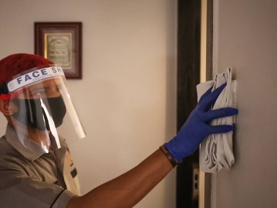 Una persona con visor facial y guantes limpiando una pared.