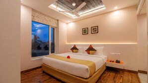 A modern hotel room with a large bed, wooden flooring, a skylight, and a night view through the window. - Mango Hotels Prangan, Bhubaneshwar (Bhubaneshwar)