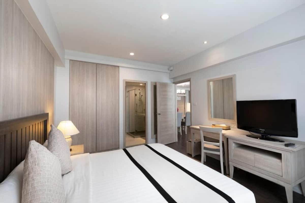A hotel room with a bed, a desk, a TV, and a walk-in closet.