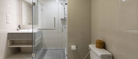 A modern bathroom with a glass-enclosed shower, a white toilet, and a granite countertop sink.