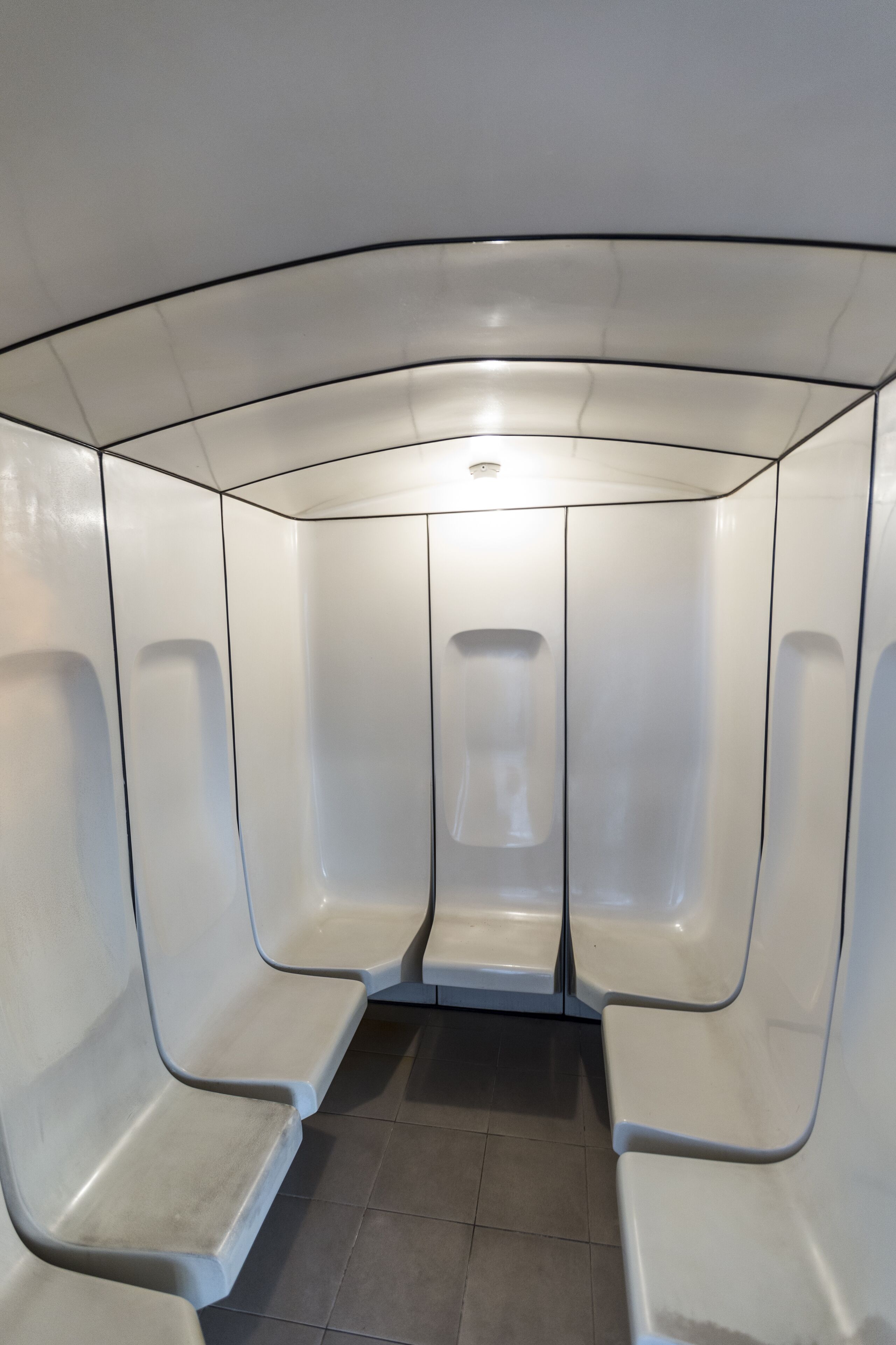 A modern, minimalist waiting area with white walls and benches.