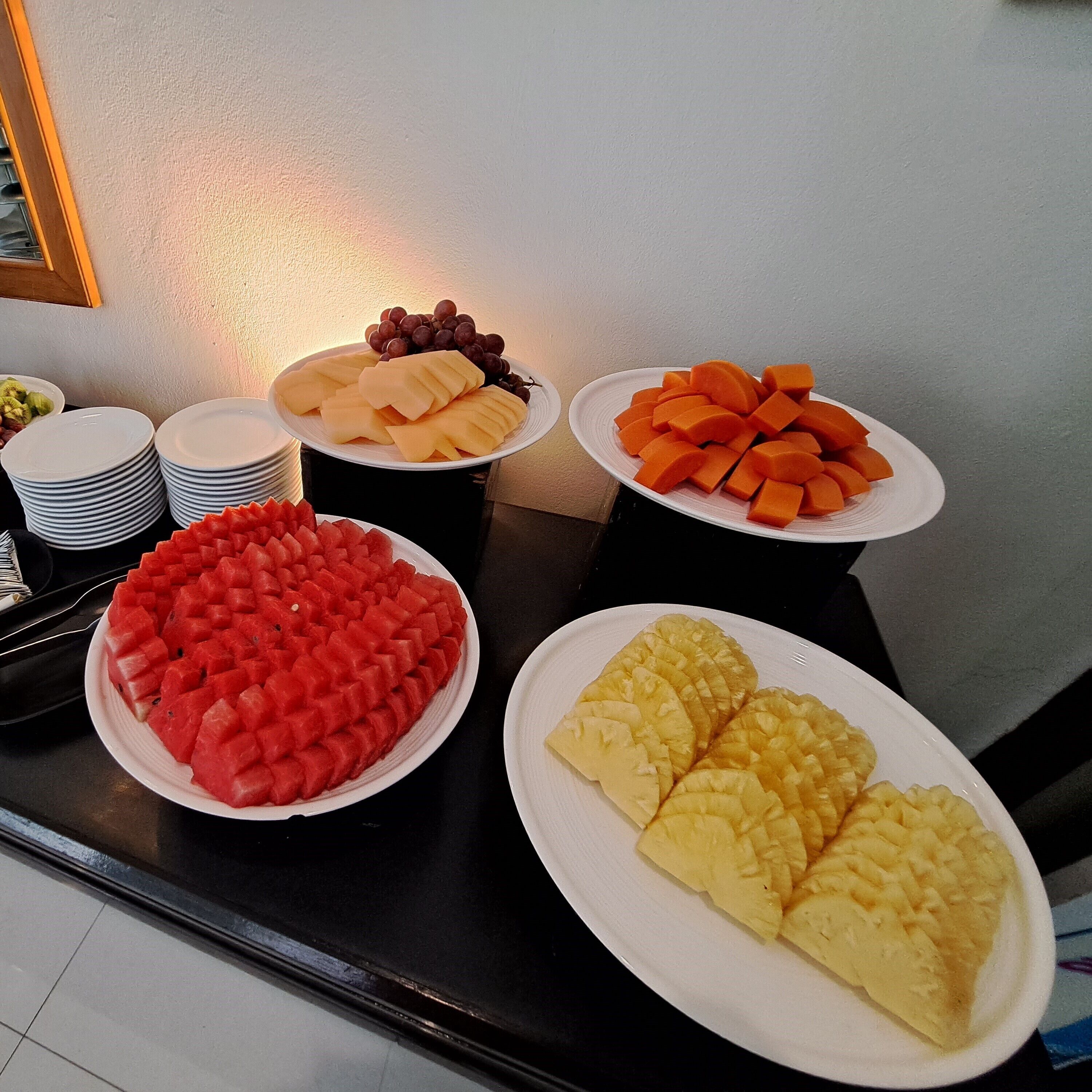 A buffet table with various fruit platters including watermelon, cantaloupe, grapes, and pineapple.