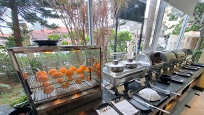Zona de bufé con diversas opciones de comida, que incluyen mariscos y salsa de chile picante, y una parrilla con alimentos ya cocinados.