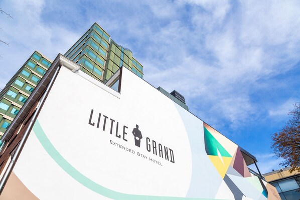 Welcome to the Little Grand Extended Stay Hotel, featuring a modern exterior with a prominent sign and contemporary architecture.