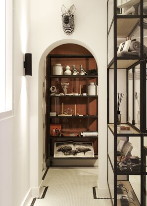 Stylish hallway leads to a cozy room with shelving and a unique arched doorway.