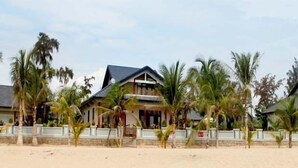 A beachfront property with multiple houses, each featuring a balcony and surrounded by palm trees. - Aniise Villa Resort (Ninh Chu)