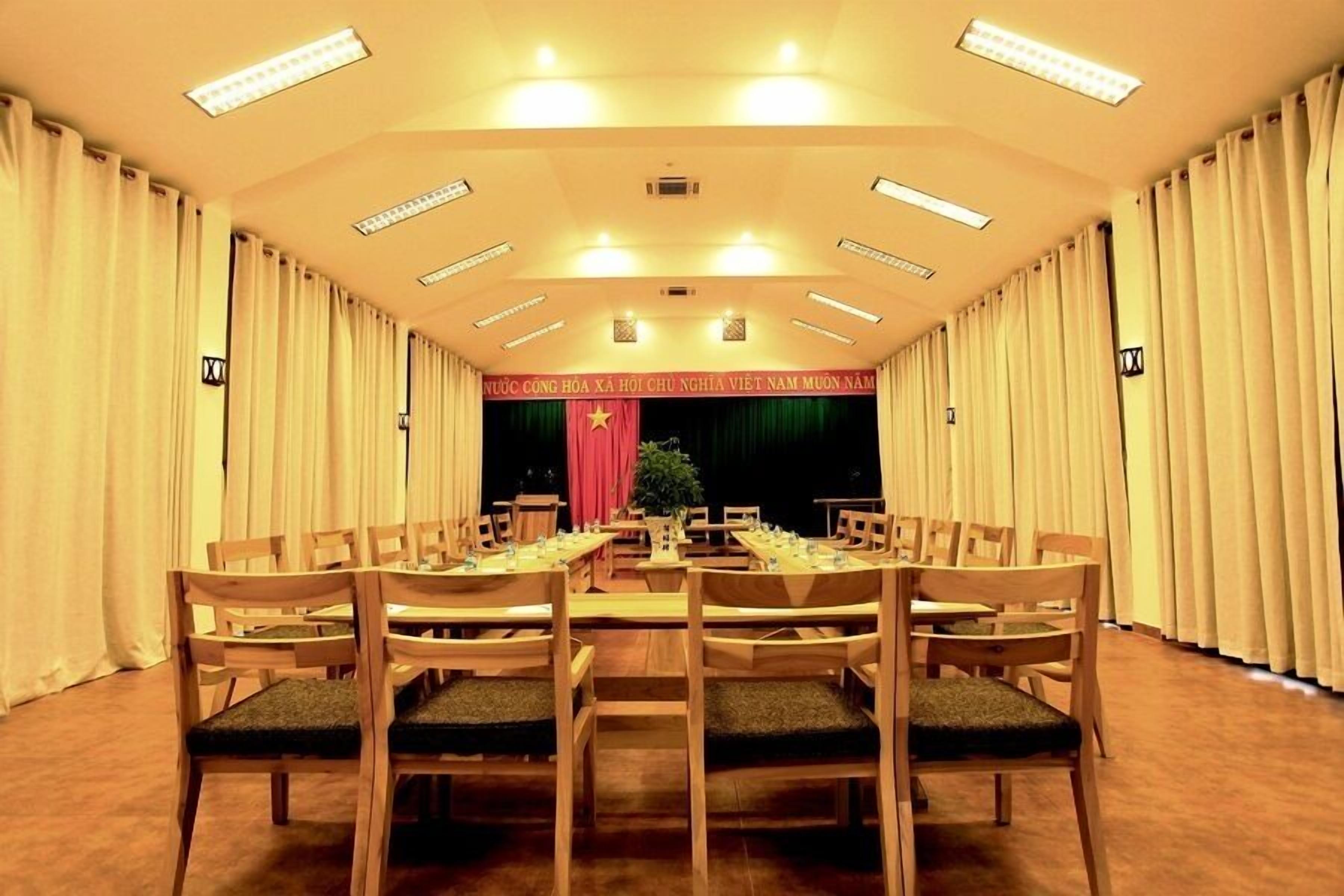 A conference room with a long table and chairs, curtains on the sides, and a red curtain with a star emblem at the front.