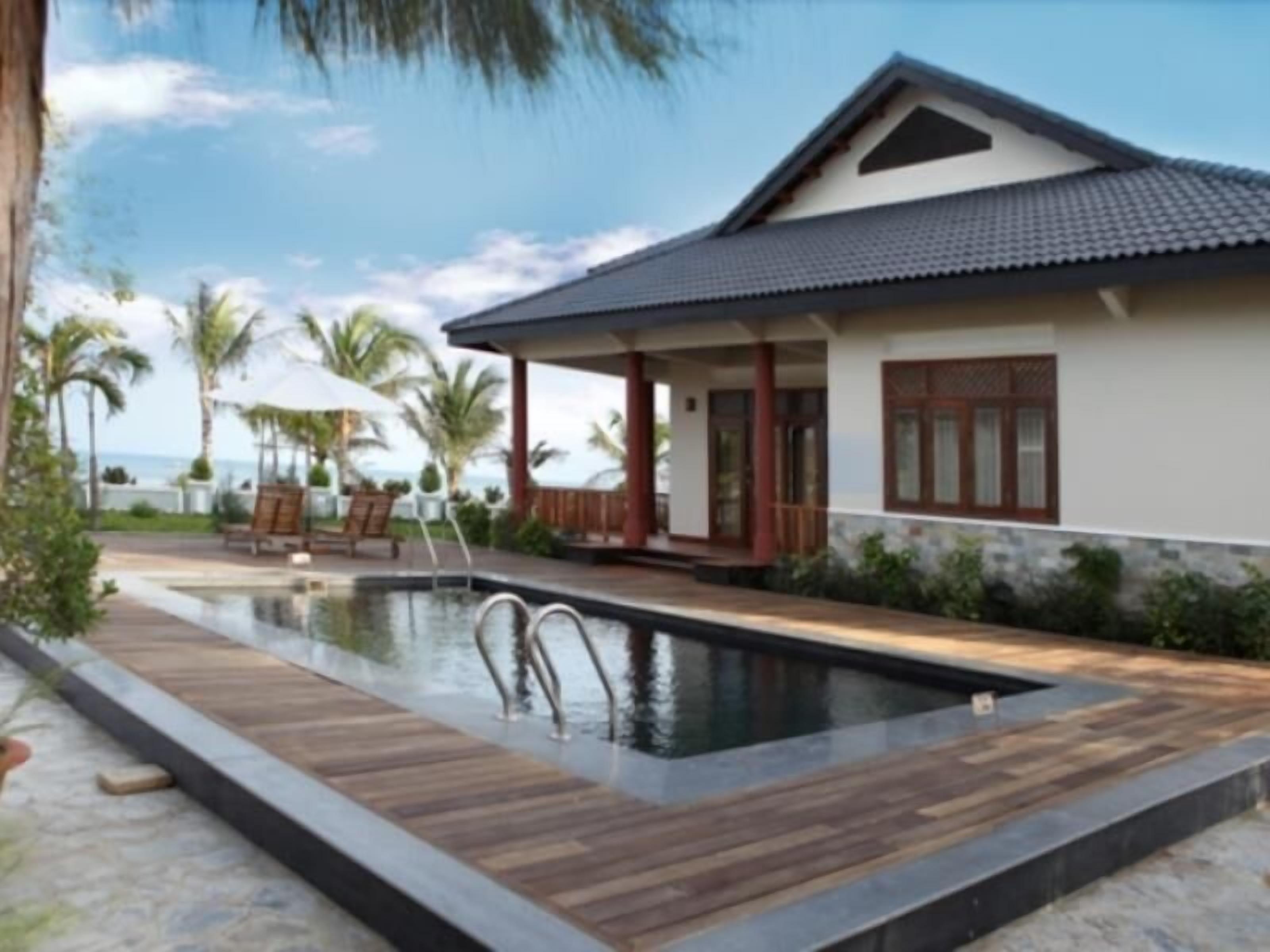 A modern house with a swimming pool, wooden deck, and a view of the ocean.
