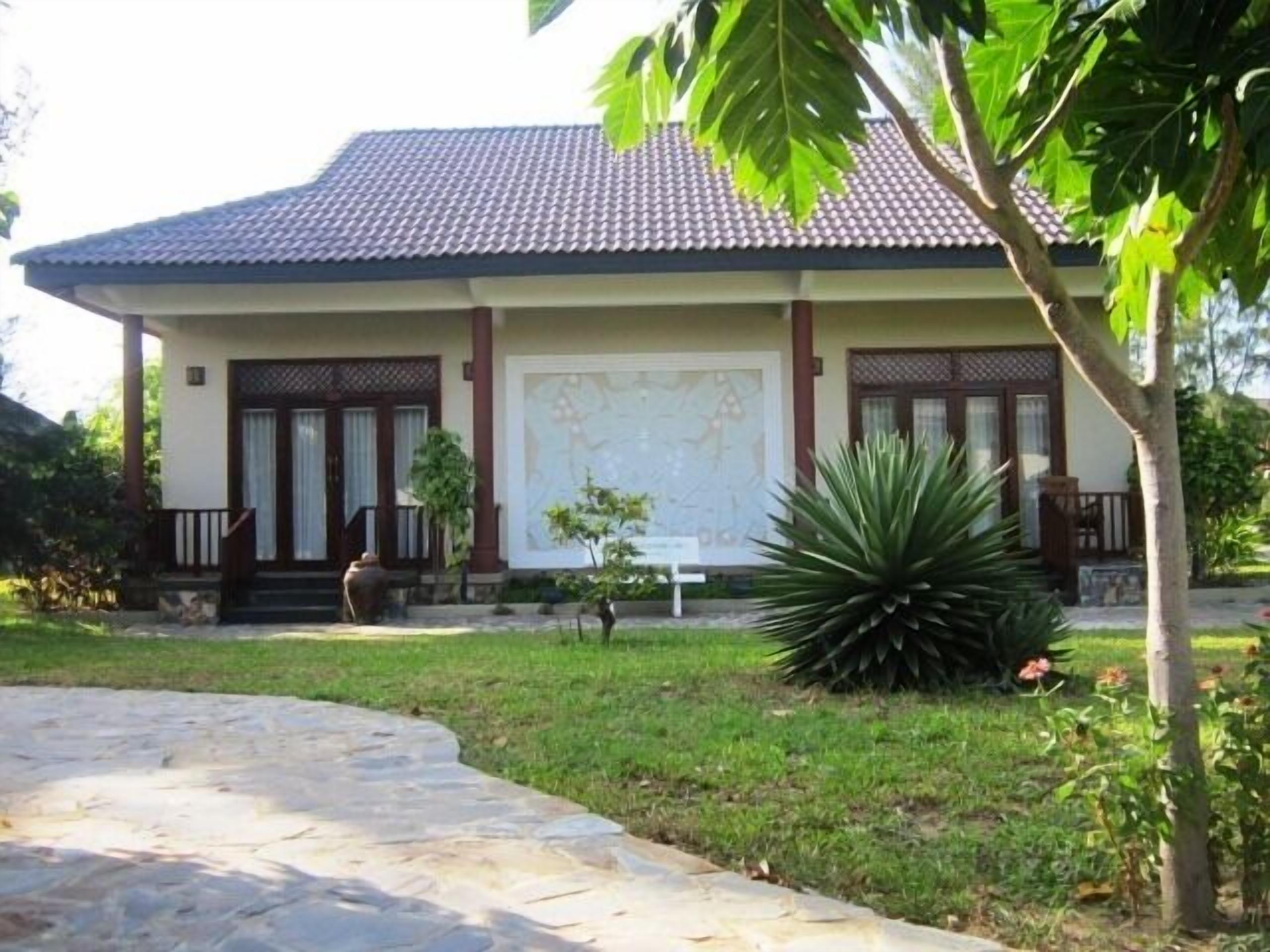 A building with a tiled roof, a large map on the wall, and a well-maintained lawn.