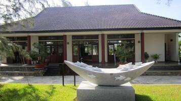 A building with a tiled roof, a large sculpture in front, and potted plants around.