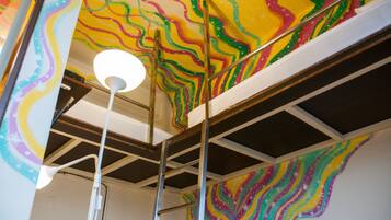 A room with a colorful abstract mural on the ceiling and a white ceiling light.