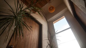 A room with a wooden door, a large window, and two potted plants. - Heng-Zhan Inn (Hengchun)