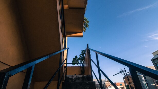 A staircase with metal railings leading to a building with a clear blue sky in the background. - Heng-Zhan Inn (Hengchun)