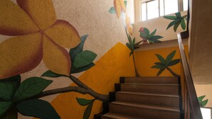 A staircase with a mural of large flowers and leaves on the walls. - Heng-Zhan Inn (Hengchun)