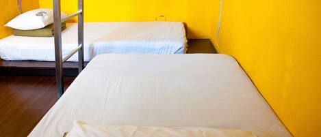 A room with two beds, one with a metal ladder, and a yellow and white wall.