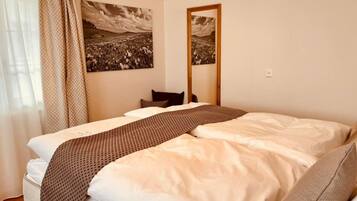 Un dormitorio con una cama, un espejo y dos cuadros de paisajes en la pared.