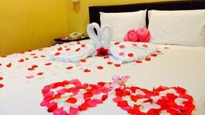A bed with rose petals arranged in a heart shape and two swans made of towels. - Grandview Hotel (Raub)