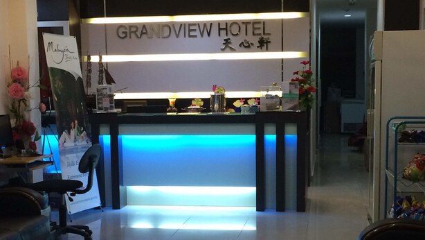 A reception desk at Grandview Hotel with a blue-lit counter, a signboard, and a reception area with a chair and a desk. - Grandview Hotel (Raub)
