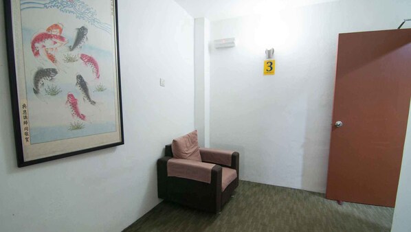 Una habitación con una obra de arte enmarcada de peces, una sola silla, una puerta y un letrero pequeño con el número 3.