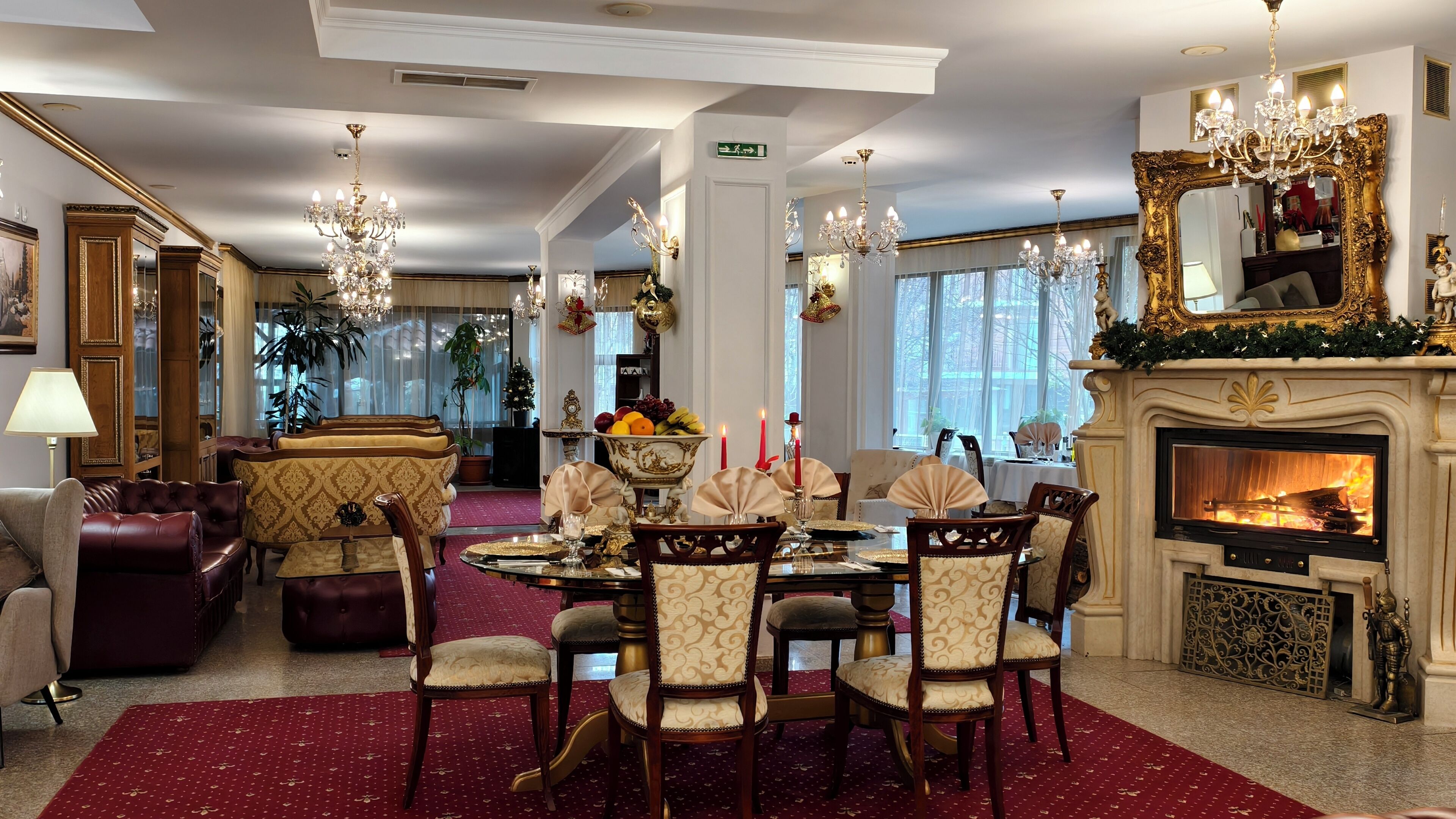 A formal dining room with a fireplace, chandeliers, and classic furniture.
