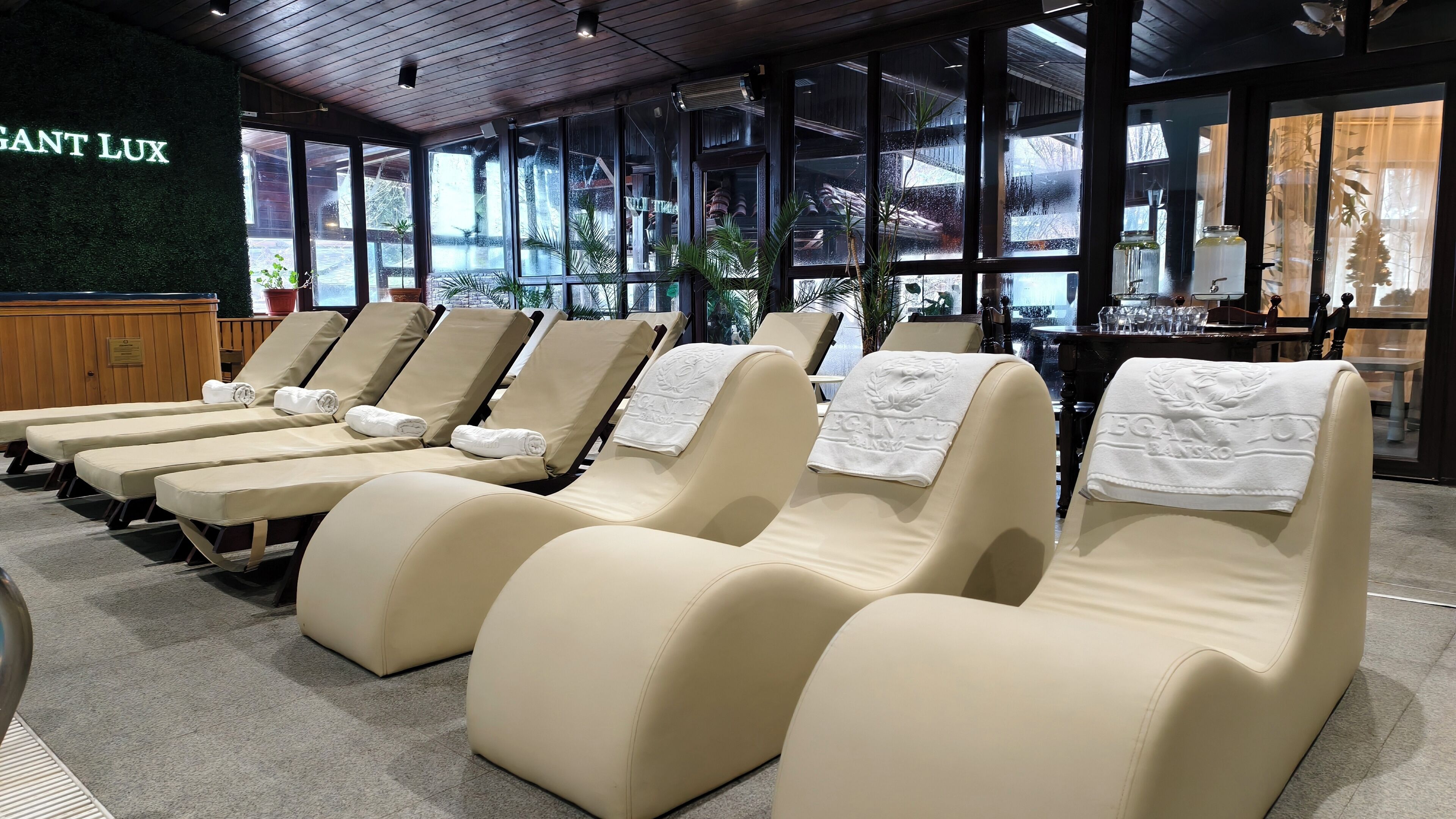 Un área de spa con sillones reclinables, un ventanal grande y un letrero en la pared que dice "GANT LUX".