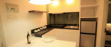 A compact kitchen with white cabinets, a black countertop, and a built-in oven.