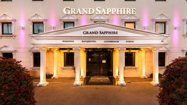 Exterior del hotel Grand Sapphire, amb façana clàssica, columnes i un cartell que indica que acull casaments, banquets, conferències i esdeveniments.