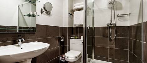 Un baño moderno con ducha envuelta en cristal, un lavabo blanco y un inodoro.