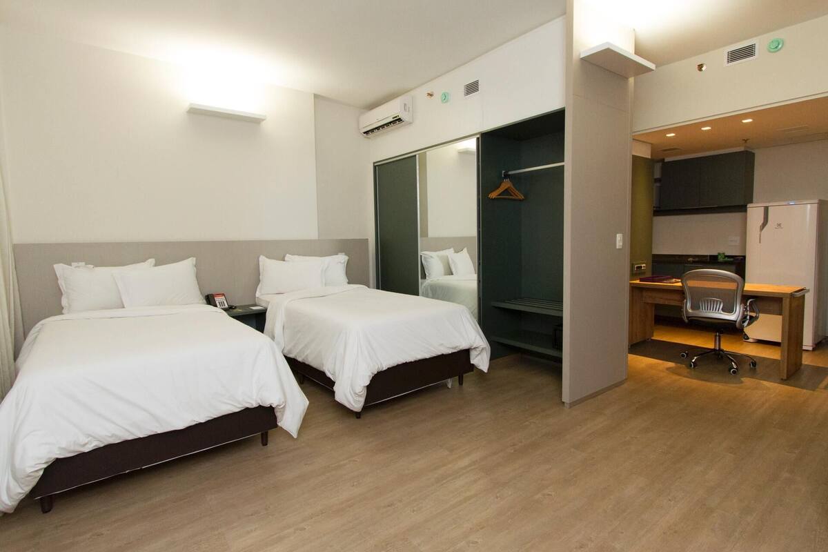 Een hotelkamer met twee bedden, een bureau, een stoel en een inloopkast.